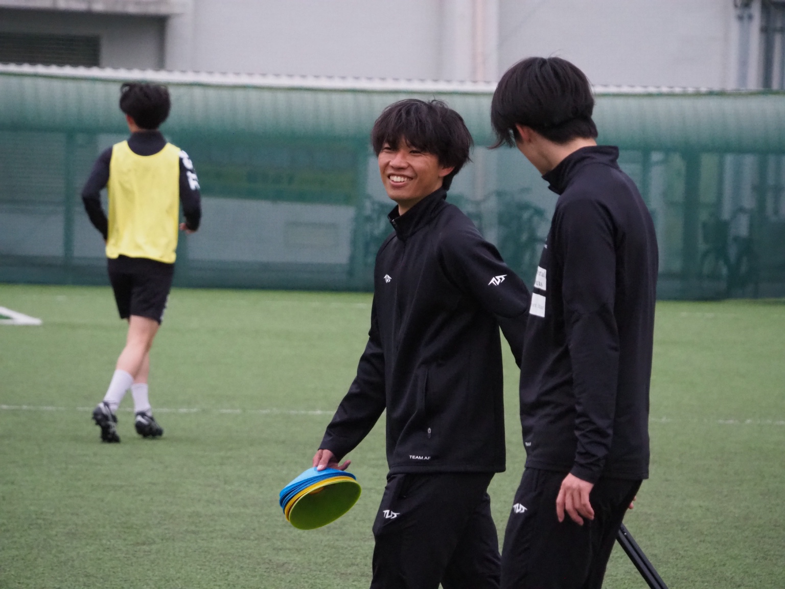 練習場でスタッフと話しながら笑う大和歩聖
